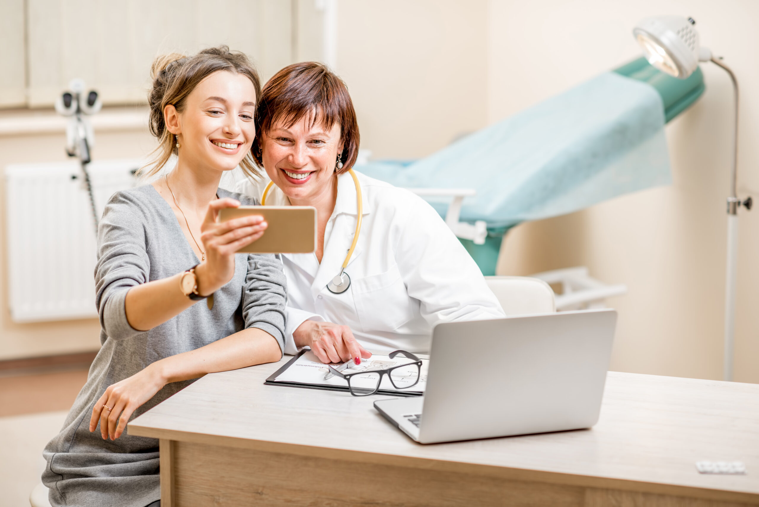 Happy patient and senior doctor making selfie photo sitting in the gynecological office