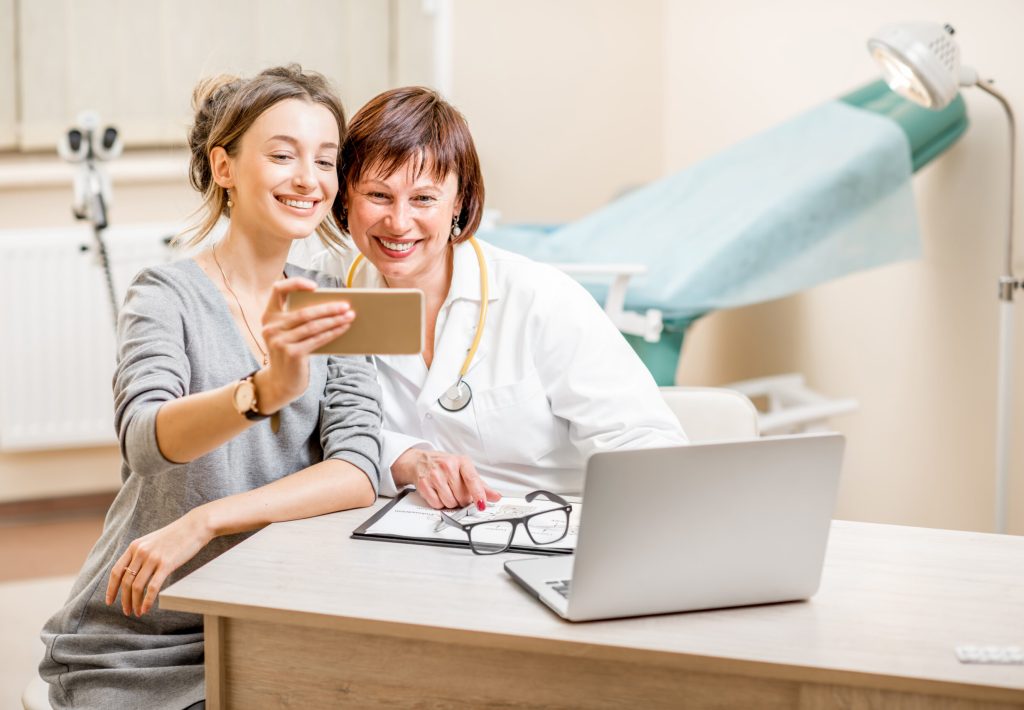 Happy patient and senior doctor making selfie photo sitting in the gynecological office